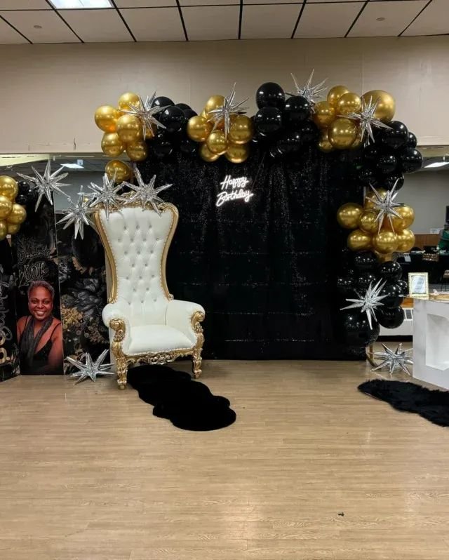 White throne with a black and gold balloon backdrop